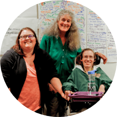 Three people smiling with a wall of notes behind them