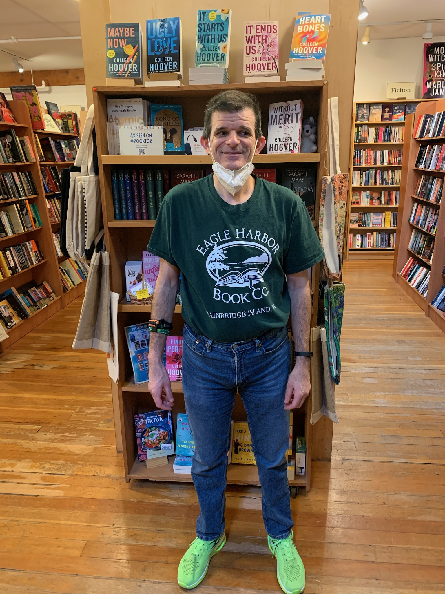 Image: Photo of Mike McLane stands in front of a book display at his job at Eagle Harbor Book Company.