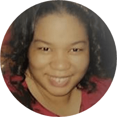 Image: a black woman with a red short and curly dark hair smiles.