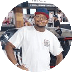 Image: William Bedford, a black man wearing glasses, a blue and red baseball hat and white t-shirt. Hands on hips, smiling.