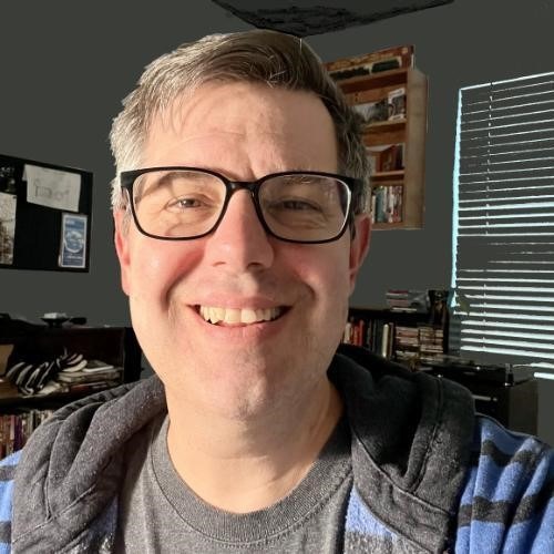 Image: Andrew Coltrin, white male with graying hair and glasses, smiling in his home office.