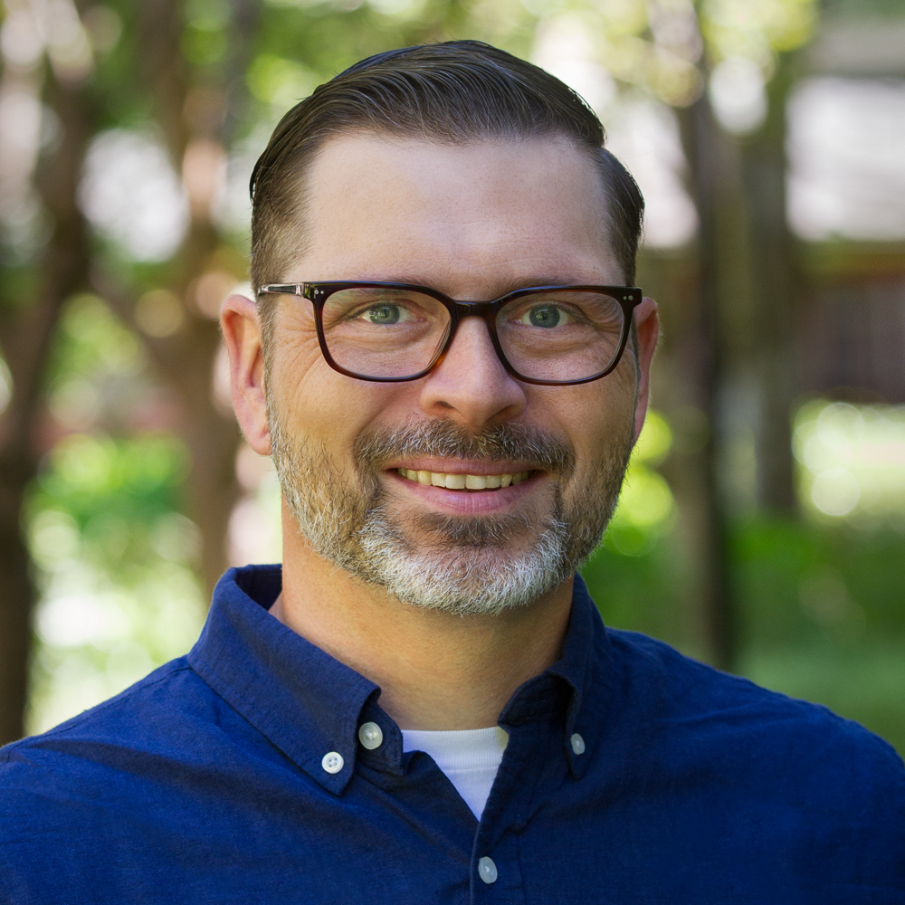 Image: Andrew Coltrin, white male with graying hair and glasses, smiling in his home office.